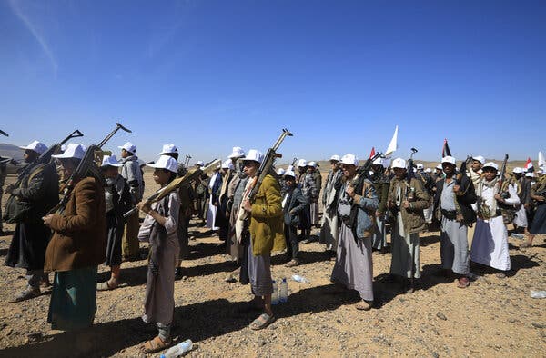 Men wearing white hats and holding firearms while standing outside.