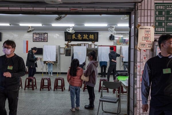 People in a room where short curtains have been draped over standing desks to create temporary voting booths with privacy.